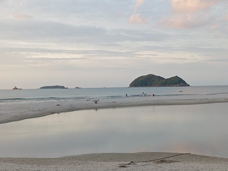 ผืนทรายเรียบและน้ำทะเลนิ่งของหาดสมิหลา มีเกาะหนูอยู่กลางทะเล
